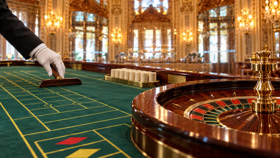 A white-gloved hand smooths the baize beside the roulette wheel