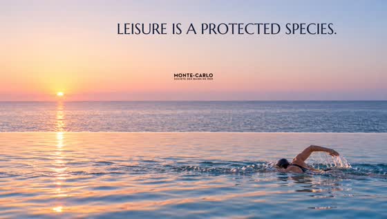 A lone swimmer crosses a sea-water pool at dawn